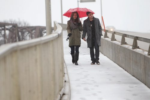 Suzanne Carpanini  and Francisco Portillo,  shelter themselves under a red umbrella as they make their way over the Assiniboine River on Kenaston Blvd, walking in the rain and the snow Saturday afternoon. Standup photo  April 14  2014 Ruth Bonneville / Winnipeg Free Press