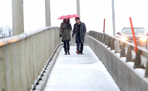 Suzanne Carpanini  and Francisco Portillo,  shelter themselves under a red umbrella as they make their way over the Assiniboine River on Kenaston Blvd, walking in the rain and the snow Saturday afternoon. Standup photo  April 14  2014 Ruth Bonneville / Winnipeg Free Press