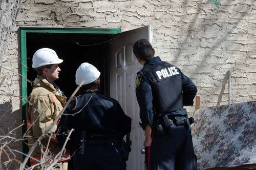 A fire official and police officers examine the door of a home on the 300 block of Enfield Crescent near Marion Street.  The basement resident died as a result of the fire.  The cause of the early morning fire is under investigation.  EMILY CUMMING / WINNIPEG FREE PRESS APRIL 16, 2014