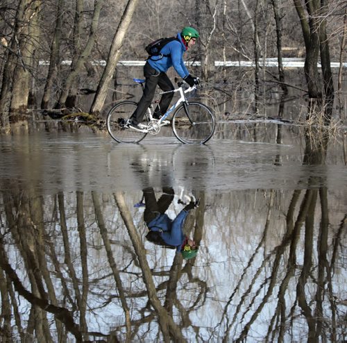 Time to Reflect. Geoff on his way to work glides through the water from the Seine River on the path through Notre Dame East Park in St. Boniface Wednesday morning. Wayne Glowacki / Winnipeg Free Press April 23   2014