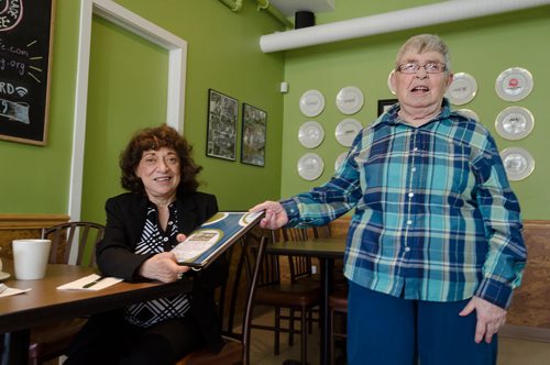 Dorothy (right) passes a menu to Tova Vickar at the L'Arche Tova Cafe.  L'Arche Winnipeg, a residential home for adults with special needs, runs a cafe where some of those residents can find jobs.  EMILY CUMMING / WINNIPEG FREE PRESS
