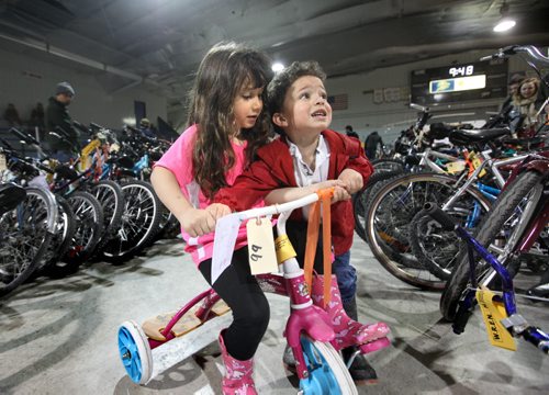 Three year old The Dixon  and his older sister Savannah - 5years jostle each other for a chance to ride one of the bikes up for auction at the city of Winnipeg's annual bike auction at Varsity View Area Saturday.  April 26, 2014 Ruth Bonneville / Winnipeg Free Pres