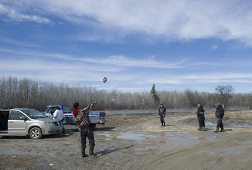 140427 Winnipeg - DAVID LIPNOWSKI / WINNIPEG FREE PRESS (April 27, 2014)  A flood fighting work crew takes a break from sandbagging to throw around a football on Peguis First Nation Reserve Sunday April 27, 2014 as the Fisher River spills over its banks.
