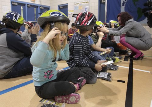 In centre, Jolene Clarke,7, and fellow students at Meadows West School received bicycle helmets and instruction how to wear them after the announcement Tuesday by Sharon Blady, Healthy Living and Seniors Minister,right,  the province will distribute 7,000 low cost bike helmets (900 helmets at no cost)  to children and youth. The Low-Cost Bike Helmet Initiative has distributed more than 97,000 helmets since 2006. see release.   Larry Kusch story   Wayne Glowacki / Winnipeg Free Press April 29   2014