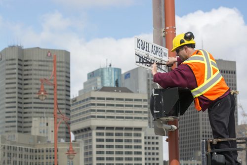 140505 Winnipeg - DAVID LIPNOWSKI / WINNIPEG FREE PRESS (May 05, 2014)  City of Winnipeg worker Kris Gustowski changes the street sign of Waterfront Dr to Israel Asper Way in front of the Canadian Museum for Human Rights Monday morning during a ceremony.