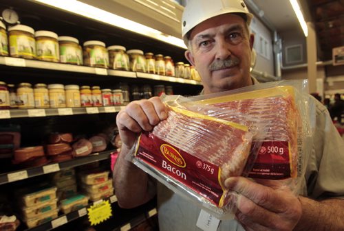 Butcher Gilbert Kohlman at Cantors Grocery Co. holds two packages of bacon, in front is a package from the latest shipment weighing in at 375g  beside a package in his cooler at a weight of a 500g. Murray McNeill story   Wayne Glowacki / Winnipeg Free Press May 6 2014