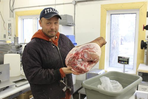01 - Clint Cavers holds up a ham leg in the Harborside Farms meat shop. BILL REDEKOP/WINNIPEG FREE PRESS May 13,2014