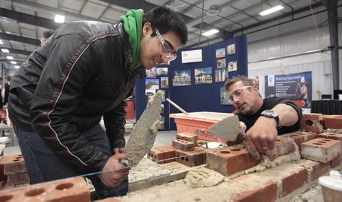 At left, Mikail Muzaki, a grade 12 student from Elmwood High School at the Manitoba Masonry Institute booth gets instruction from mason Tony Guerreiro. About 1800 high school students attended the 6th annual Manitoba Construction Career Expo held at the Red River Exhibition Place. Students had an opportunity to try their hand at construction-related trades (welding, painting, roofing, piping ect.) at 34 interactive booths/displays.  see release Wayne Glowacki / Winnipeg Free Press May 14 2014
