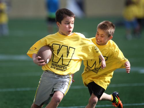 Ten year old Christian Woo tries to tackle his older brother Kolten - 12yrs as they play football on Investors Group Field with other kids during the Doug Brown KidSport Winnipeg Football Camp Saturday morning.  Brown and volunteers with the CFL volunteer their time to teach kids in the fundamentals of football.   Standup photo May 17, 2014 Ruth Bonneville / Winnipeg Free Press