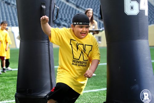 Rocco Linklater is all smiles as he makes his way around bags during drills  while learning to play football on Investors Group Field with other kids during the Doug Brown KidSport Winnipeg Football Camp Saturday morning.  Brown and volunteers with the CFL volunteer their time to teach kids in the fundamentals of football.   Standup photo May 17, 2014 Ruth Bonneville / Winnipeg Free Press