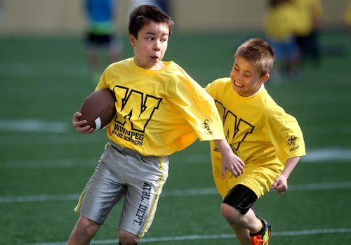 Ten year old Christian Woo tries to tackle his older brother Kolten - 12yrs as they play football on Investors Group Field with other kids during the Doug Brown KidSport Winnipeg Football Camp Saturday morning.  Brown and volunteers with the CFL volunteer their time to teach kids in the fundamentals of football.   Standup photo May 17, 2014 Ruth Bonneville / Winnipeg Free Press