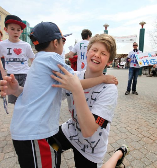 Eleven year old Ethan Degroot gives a young boy a hug along with other members of his team of huggers at the Forks Saturday.  The team of huggers took part in Voices Free Hug Day 2014, a youth initiative supported by team leader - Steve Degroot (fman on ar right, sunglasses) that was created to remember foster kids in care. See Alex Paul's story.  May 17, 2014 Ruth Bonneville / Winnipeg Free Press