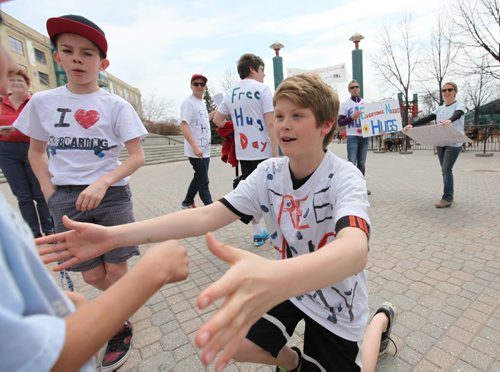 Eleven year old Ethan Degroot gives a young boy a hug along with other members of his team of huggers at the Forks Saturday.  The team of huggers took part in Voices Free Hug Day 2014, a youth initiative supported by team leader - Steve Degroot (fman on ar right, sunglasses) that was created to remember foster kids in care. See Alex Paul's story.  May 17, 2014 Ruth Bonneville / Winnipeg Free Press