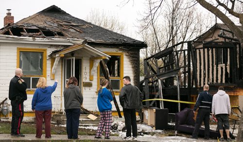 Residents of a fire damaged home on Jefferson Avenue near Scotia Street react to seeing the aftermath Monday morning. Bradley Larocque (in black) noticed someone running from a house next door before 8am, and then heard a "whoosh" as fire engulfed the home that was under construction. He got all six other residents out of the house before there were any injuries. Three of five cats were rescued, and another was seen escaping. In total four houses were damaged, fire and police continue to investigate.  140519 - Monday, May 19, 2014 - (Melissa Tait / Winnipeg Free Press)