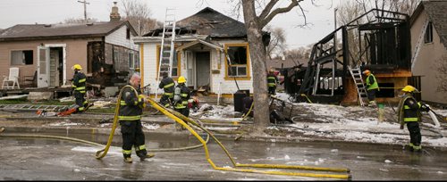 Winnipeg Fire Paramedic investigators at the scene of a fire damaged home on Jefferson Avenue near Scotia Street. In total four houses were damaged, fire and police continue to investigate.  140519 - Monday, May 19, 2014 - (Melissa Tait / Winnipeg Free Press)