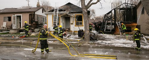 Winnipeg Fire Paramedic Servicemen clean up their equipment at the scene of a fire damaged home on Jefferson Avenue near Scotia Street. In total four houses were damaged, fire and police continue to investigate.  140519 - Monday, May 19, 2014 - (Melissa Tait / Winnipeg Free Press)