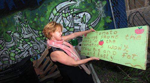 Executive director Beverly Burkard admires hand painted signs in the garden at the Red Road Lodge, one of the featured buildings in Doors Open Winnipeg, a free event happening this weekend. This once infamous Main Street hotel has been transformed into a 40-room transitional housing facility providing safe, affordable housing  with support services to at-risk individuals. May 29, 2014 - (Phil Hossack / Winnipeg Free Press)