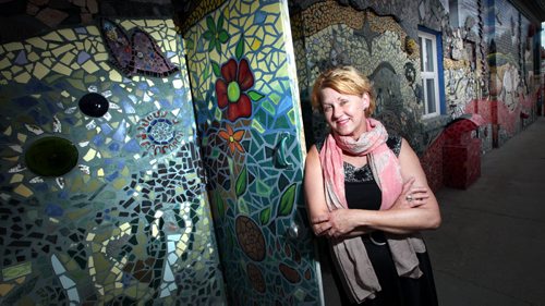 Executive director Beverly Burkard poses with a giant mosaic mural decorating the west wall of The Red Road Lodge, one of the featured buildings in Doors Open Winnipeg, a free event happening this weekend. This once infamous Main Street hotel has been transformed into a 40-room transitional housing facility providing safe, affordable housing  with support services to at-risk individuals. May 29, 2014 - (Phil Hossack / Winnipeg Free Press)