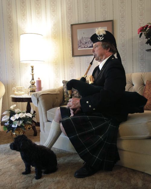49.8 INTERSECTION.  Bagpiper Robyn McCombe  plays his  Shuttle Pipes at home with his dog Bella. . This is for an Intersection piece on bagpipers who play at weddings. Dave Sanderson story Wayne Glowacki / Winnipeg Free Press June 2 2014