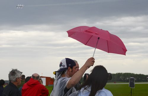 Josh Riedner holds an umbrella for Sabrina Possia as they watch the Snowbirds perform at the Southport Airport in Portage la Prairie. The show was in honour of the Royal Canadian Air Force's 90th anniversary. Sarah Taylor / Winnipeg Free Press