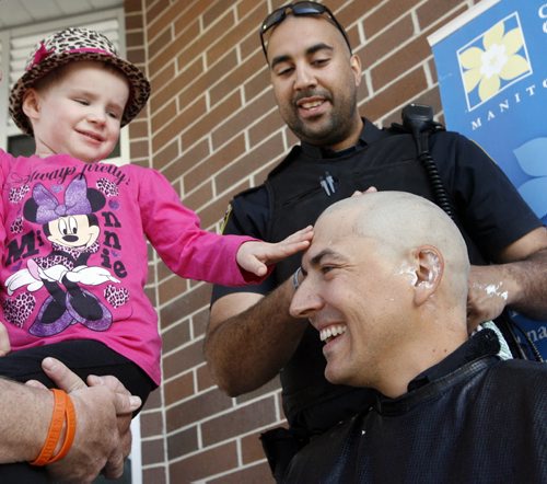 Four year old Katelyn Cairns touches the bald head of Winnipeg Police Cst. Gaetan Beauchemin who had his head shaved by Cst. Damian Drzewiec on the front steps of the West District Police Station Thursday morning. Cst. Beauchemin got his hair cut in solidarity and support of his previous police partner's daughter Katelyn who is currently undergoing chemotherapy for Leukemia.  Gaetan also raised $1,785 for the  Canadian Cancer Society.   Wayne Glowacki / Winnipeg Free Press June 4 2014see release. Wayne Glowacki / Winnipeg Free Press June 5 2014