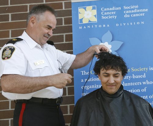 Winnipeg Police Inspector Rick Guyader starts running the hair clipper through the locks of Cst. Gaetan Beauchemin on the front steps of the West District Police Station Thursday morning, Gaetan wanted to support and show solidarity with his previous police partner's daughter Katelyn Cairns who is currently undergoing chemotherapy for Leukemia. Gaetan head shaving raised $1,785 for the Canadian Cancer Society. see release. Wayne Glowacki / Winnipeg Free Press June 5 2014