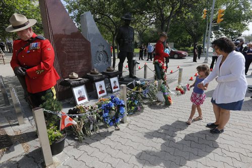 LOCAL Winnipeg RCMP D Division held their own memorial service for slain members in Moncton NB. On Portage Ave  Tuesday Morning . Abigail Bell age 4 and a half laid a bouquet of flowers at the RCMP memorial for  members who lost their lives while on duty with her mother Jacquie Bell  June 10 2014 / KEN GIGLIOTTI / WINNIPEG FREE PRESS