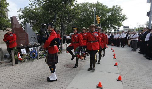 RCMP Chief Superintendent  (left with wreath) Scott Kolody with honour guard  lays wreath . Winnipeg RCMP D Division held their own memorial service for slain members in Moncton NB. On Portage Ave  Tuesday Morning . Abigail Bell age 4 and a half laid a bouquet of flowers at the RCMP memorial for  members who lost their lives while on duty with her mother Jacquie Bell  June 10 2014 / KEN GIGLIOTTI / WINNIPEG FREE PRESS