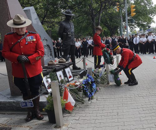 during the ceremony  that included RCMP Chief Superintendent  ( in photo) Scott Kolody with honour guard  lays wreath . Winnipeg RCMP D Division held their own memorial service for slain members in Moncton NB. On Portage Ave  Tuesday Morning .  Äì the short wreath laying ceremony involved RCMP officers , staff at D Division , Wpg City Police  and members of the public Dignitaries included Mb Attorney General Andrew Swan , WPS Chief Devon Clunis   MB premier Greg Selinger June 10 2014 / KEN GIGLIOTTI / WINNIPEG FREE PRESS