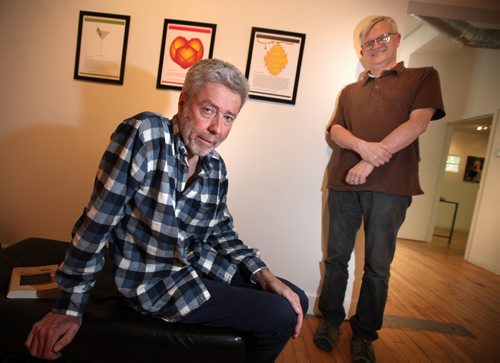 Cliff Eyland (left) and U of M professor George Toles  pose with some of their work hung behind them at Gurevich Fine Art Gallery Tuesday. Eyland has illustrated Facebook updates by Toles for an exhibit opening next Monday called Facebook Posts. See Kevin Prokosh story. June 10, 2014 - (Phil Hossack / Winnipeg Free Press)