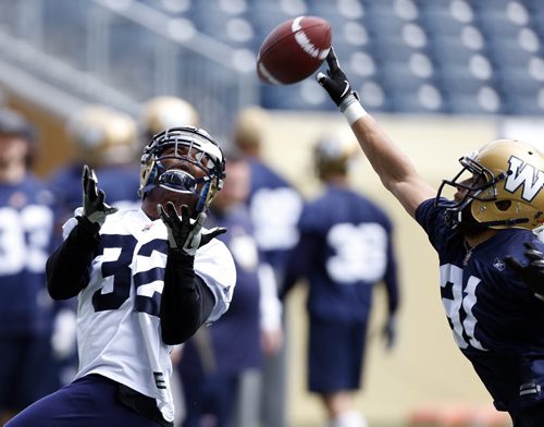 #32 RB  Nic Grigsby  makes catch even though #31 LB Teague Sherman appears to tip the ball during Blue Bomber training camp , preseason practice feature for Lawless  June 11 2014 / KEN GIGLIOTTI / WINNIPEG FREE PRESS