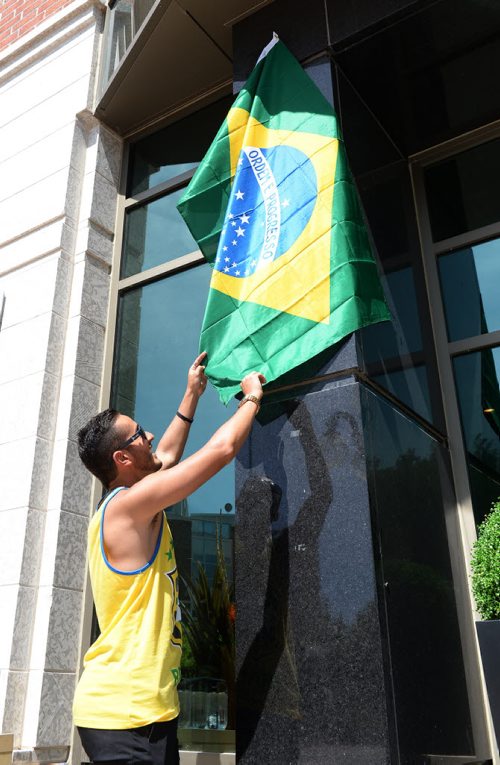 Karius Lima set up a Brazilian flag outside Carnaval Restaurant for the World Cup pre game party. Sarah Taylor / Winnipeg Free Press