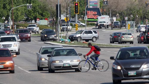 A Cyclist navigates through heavy traffic at Bishop Grandin Blvd and Pembina Hyw Thursday afternoon-Last Monday a 69 yr old man was hit by a car while cycling to the Winnipeg Blue Bombers game at Investors Group Field- He died from his injuries-  See Geoff Kirybson story- June 12, 2014   (JOE BRYKSA / WINNIPEG FREE PRESS)