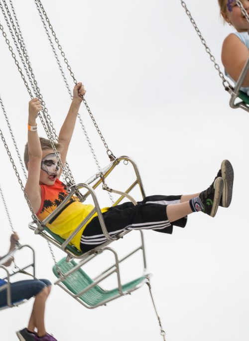 Myles Miller, 8, concentrates on his swing ride high above the Red River Ex grounds on opening day Friday. Clouds and the threat of rain kept the number of visitors down. 140613 - Friday, June 13, 2014 - (Melissa Tait / Winnipeg Free Press)