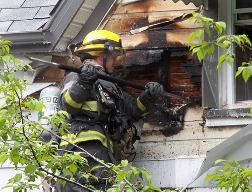 A Winnipeg Firefighter works at ripping off siding at 546 Flora Ave Monday afternoon after a electrical fire spread inside the walls No injuries reported-  Breaking News- June 16, 2014   (JOE BRYKSA / WINNIPEG FREE PRESS)
