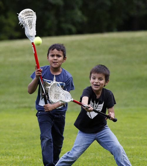 Stdup .Brothers left Mason Tait age 8 and his brother Merek age 6 play catch with lacrosse  sticks  with their dad at Kildonan Park  in sunny and 21 conditions . June 16 2014 / KEN GIGLIOTTI / WINNIPEG FREE PRESS