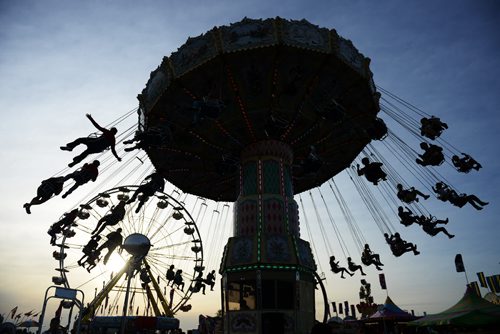 Red River Ex thrill seekers hang suspended from a spinning swing as the sun sets on Wednesday night at the Red River Ex. Sarah Taylor / Winnipeg Free Press