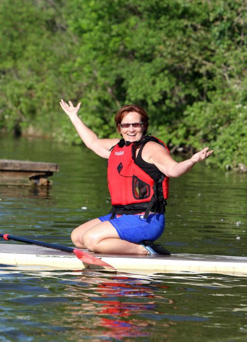 Barb Smith celebrates getting on her board during a WAVpaddling stand-up paddle-boarding lesson at the FortWhyte Alive Adventure Site in Winnipeg, Man., on Wed., June 18, 2014. Photo by Jason Halstead/Winnipeg Free Press RE: Intersection feature