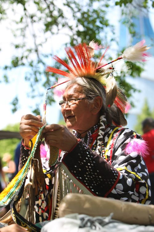 George Abraham mends his traditional dance costume after performing in the Pow Wow on the  fields at the Forks National Historic site for Aboriginal Day Saturday afternoon during the Grand Entry. Standup photo.  June 21, 2014 Ruth Bonneville / Winnipeg Free Press