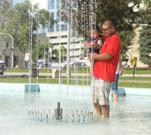 Gerald Lacquette and son Braden cools down while they play in the fountain at Memorial Park on Saturday. Sarah Taylor / Winnipeg Free Press