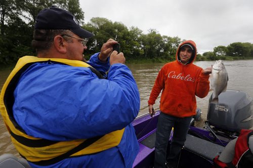 Raising awareness  first person Fish Story by Oliver Sachgau , trying to catch fish on the Red River near Selkirk . in pic left Guide Dan Goulet uses smartphone to take photo for social media of fellow fisher Mike  Morgado and his Silver Drum Bass before releasing back into the Red River . June 24 2014 / KEN GIGLIOTTI / WINNIPEG FREE PRESS