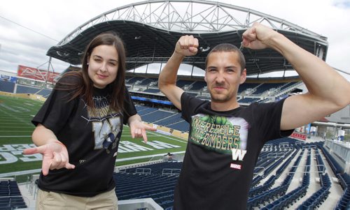 Bomber Store employees Samantha LaPointe and Quinn Smith ham it up with the new Marvel comic character Winnipeg Blue Bomber T-Shirts at Investors Group Centre. BORIS MINKEVICH / WINNIPEG FREE PRESS  June 25, 2014