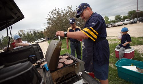 left to right-Tailgaters Cory Rach, Pat Mulville, Kurt Kowalchuk and six yr old Brady Rach warm up a few burgers in the parking lot before the Bomber's Home Opener Thursday evening. See Nick Martin's tale. June 26, 2014 - (Phil Hossack / Winnipeg Free Press)