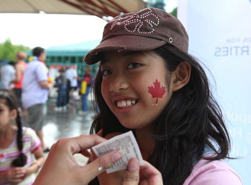 Nine year old Haya Grefalda gets a red maple leaf sticker on her cheek at one of the kids kiosks at the Forks during Multiculturalism Day Saturday afternoon. The free event is a interactive, family event featuring performers, entertainers, artisans and displays, all in celebration of Manitobas cultural diversity. Families will have the opportunity to engage with a multitude of cultures through music, dance and storytelling throughout the day Standup photo  June 28, 2014 Ruth Bonneville / Winnipeg Free Press