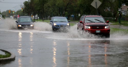 Vehicles splash through a deep puddle at Notre Dame Avenue and Border Street, Sunday, June 29, 2014. (TREVOR HAGAN/WINNIPEG FREE PRESS)