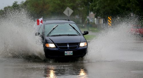 Vehicles splash through a deep puddle at Notre Dame Avenue and Border Street, Sunday, June 29, 2014. (TREVOR HAGAN/WINNIPEG FREE PRESS)