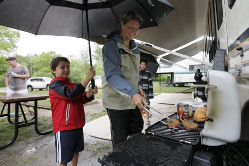 June 29, 2014 - 140629  -  Kim Macaulay cooks some steaks under the umbrella of Tristan Szajewski as his cousin Ethan looks on at the Bird's Hill Park camp site Sunday, June 29, 2014. John Woods / Winnipeg Free Press