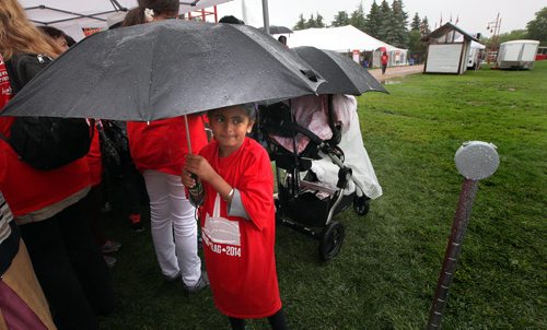 A young participant waits under an umbrella to participate in the formation  of a human flag formed despite the weather at the Forks Tuesday.  See Oliver's story. July 1, 2014 - (Phil Hossack / Winnipeg Free Press)