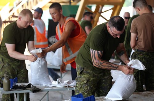 Bmbr. Jonathan Kaiser, right, one of the soldiers from CFB Shilo, who along with members of the Portage la Prairie Municipality, were filling sandbags at the Portage Yard, Saturday, July 5, 2014. (TREVOR HAGAN/WINNIPEG FREE PRESS)
