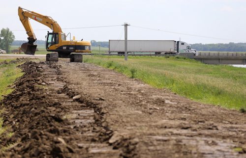 Construction crews work to bulk up the east side of the Portage Diversion near Highway 1, Saturday, July 5, 2014. (TREVOR HAGAN/WINNIPEG FREE PRESS)